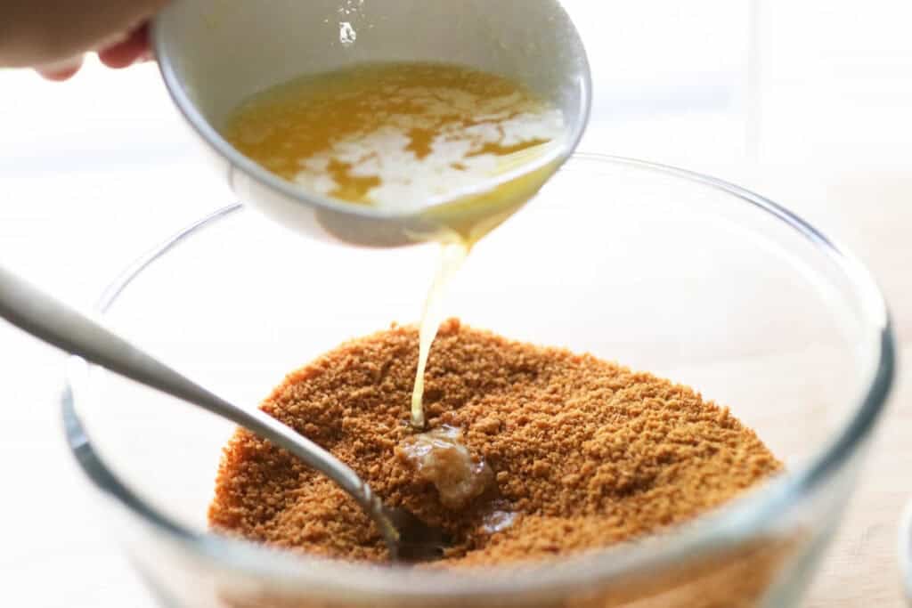 Pouring butter into graham cracker crumbs