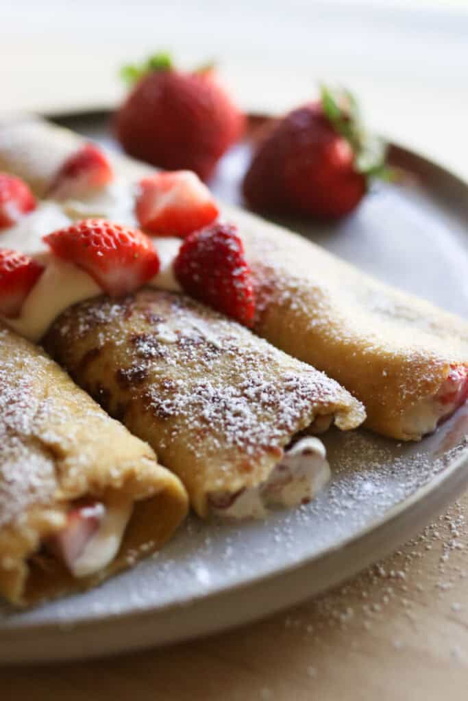 fresh milled crepes topped with berries and powdered sugar and cream