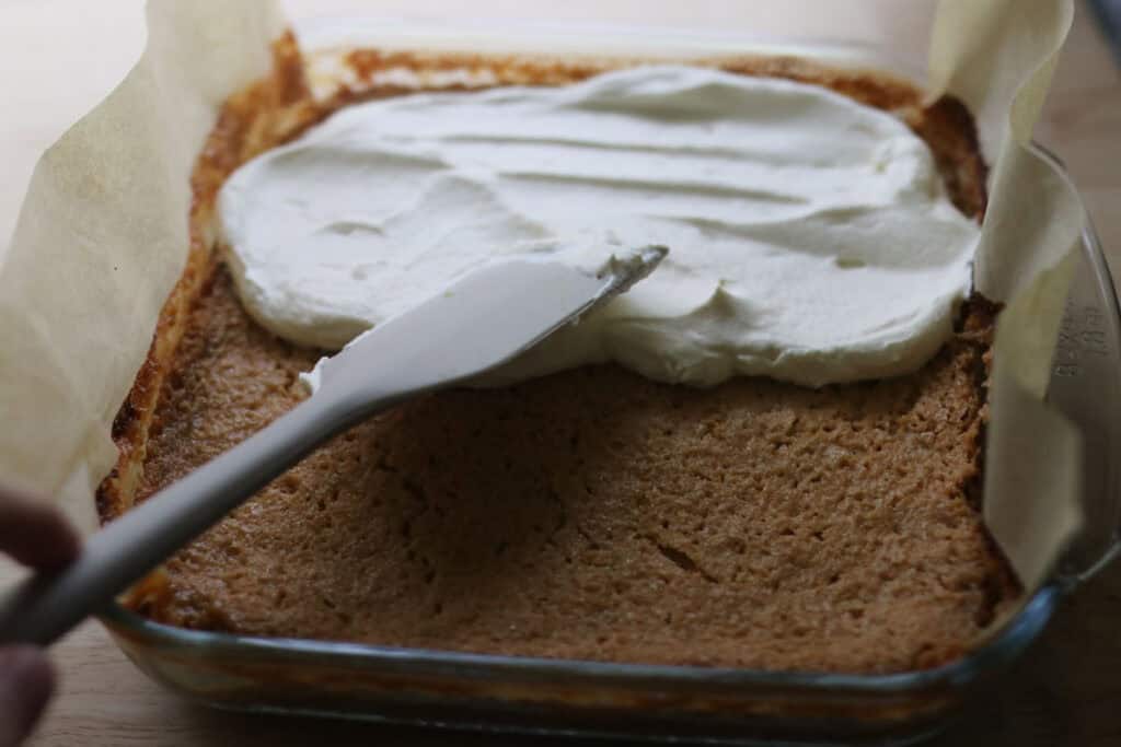 Spreading homemade whipped cream over freshly milled key lime pie bars