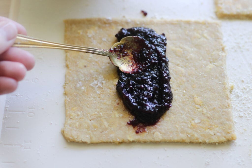 Blueberry jam being spread onto a freshly milled nutrigrain bar