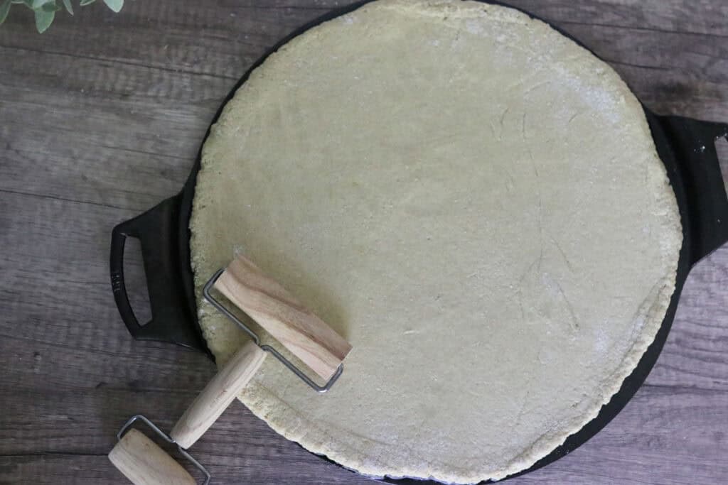 pizza crust that has been rolled out on cast iron pan