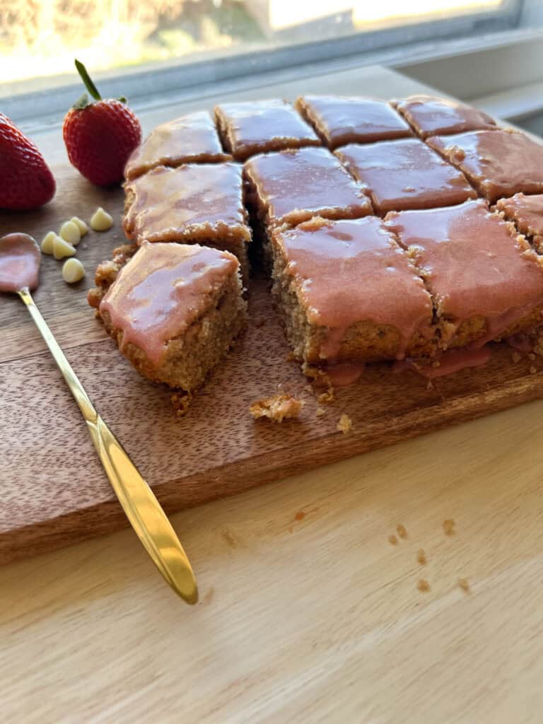 strawberry brownies that have been sliced with strawberries in background