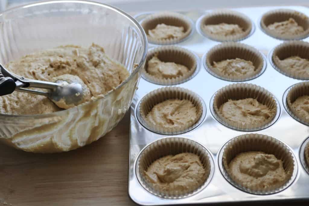 cupcake batter being scooped into muffin pan