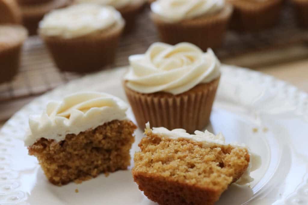 three vanilla cupcakes on a plate with icing on top