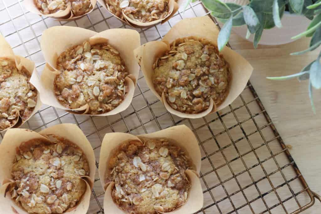 fresh milled sourdough banana crumble muffins cooling on a wire rack with a plant beside it