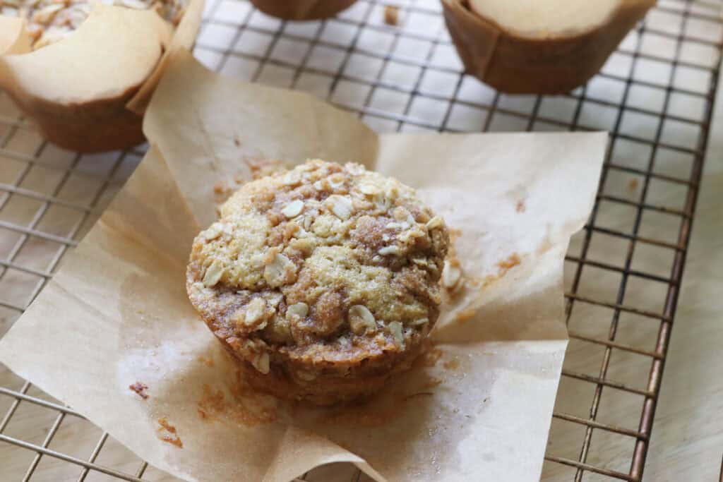 a fresh milled sourdough banana crumble muffin with a muffin liner that has been pulled back