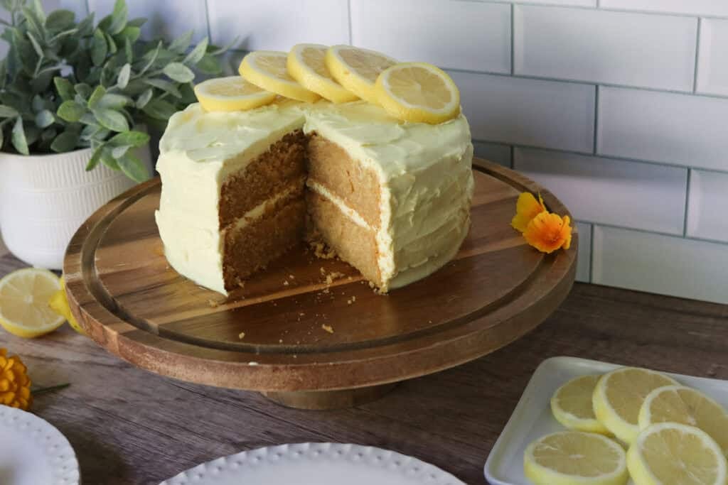 a freshly milled lemon chantilly cake with lemons and flowers on a cake stand