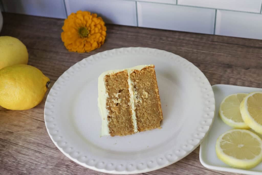 a slice of freshly milled lemon chantilly cake on a white plate with lemons