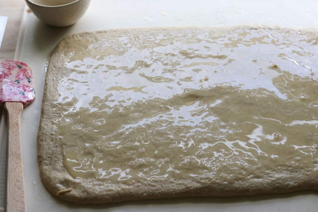 melted butter spread on dough for fresh milled twisted apple cinnamon loaf
