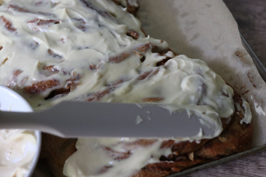 spreading icing over fresh milled twisted apple cinnamon loaf