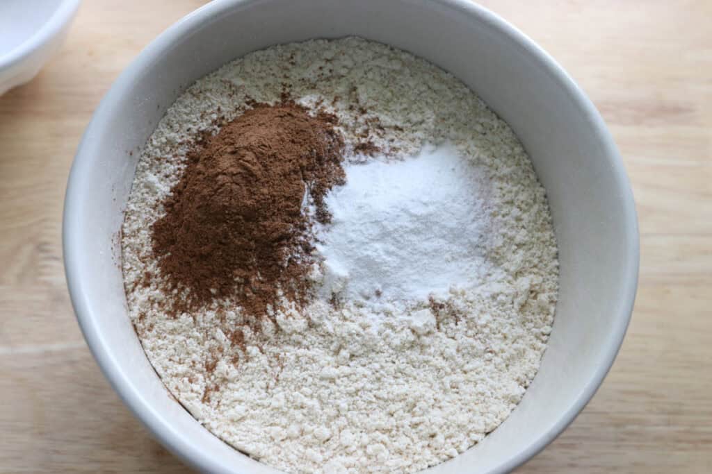 flour and cinnamon in a white bowl to make freshly milled apple cinnamon streusel muffins
