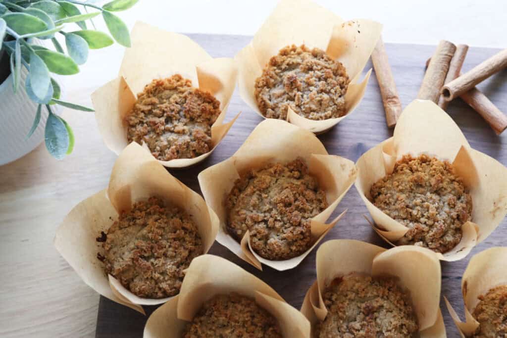 freshly milled apple cinnamon streusel muffins on a cutting board with cinnamon sticks