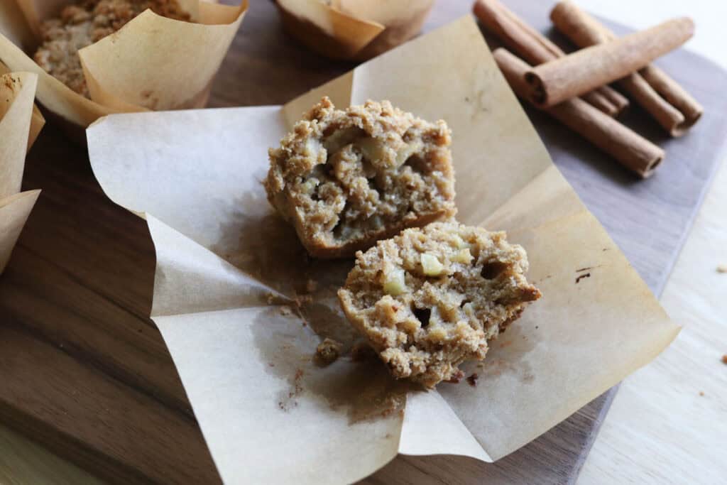 a freshly milled apple cinnamon streusel muffin cut in half on a piece of parchment