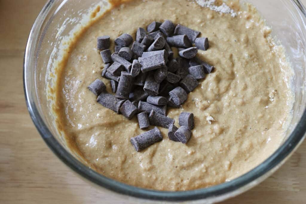 chocolate chips on top of freshly milled chocolate chip cappuccino muffin batter