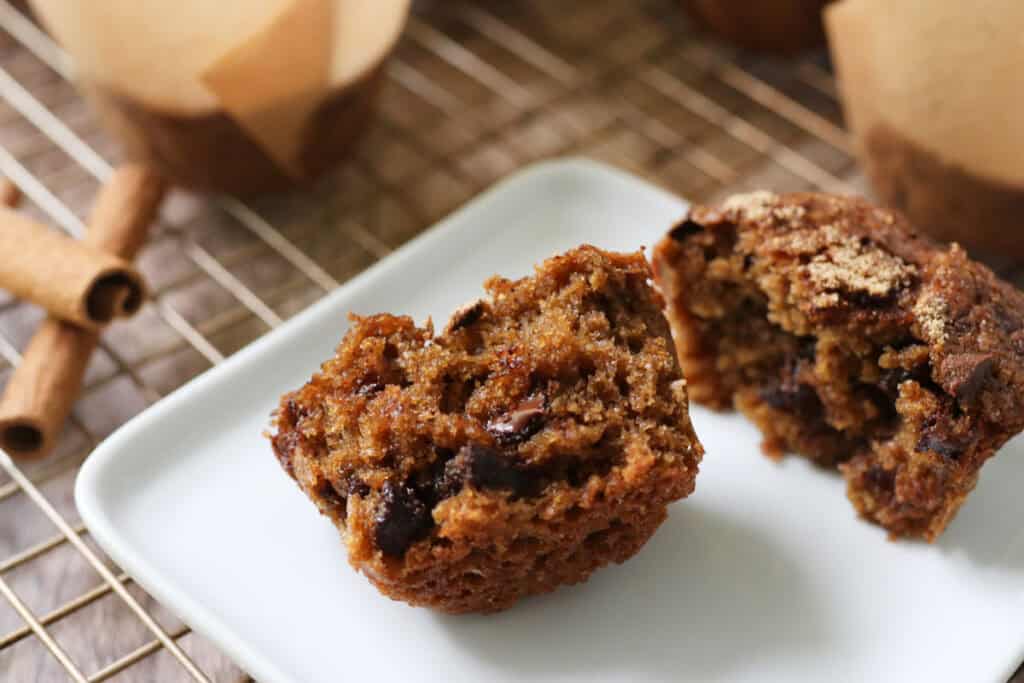 a freshly milled chocolate chip cappuccino muffin cut in half on a white plate