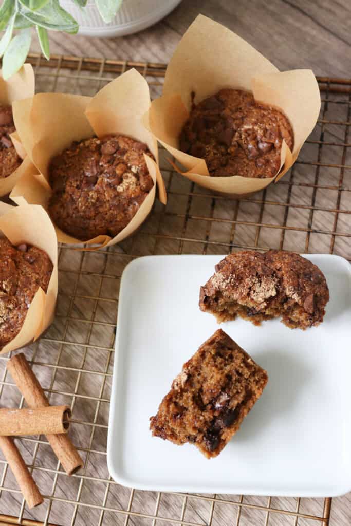 freshly milled chocolate chip cappuccino muffins on a wire rack with one on a white plate that is cut in half