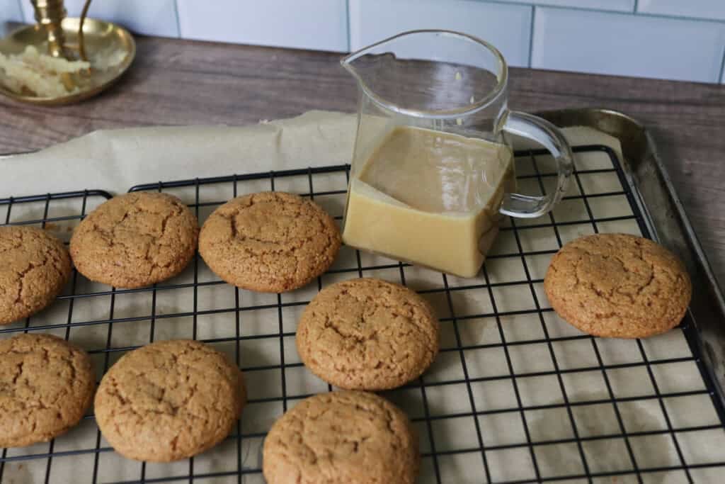 fresh milled maple brown sugar cookies on a wire rack with maple icing in a pitcher