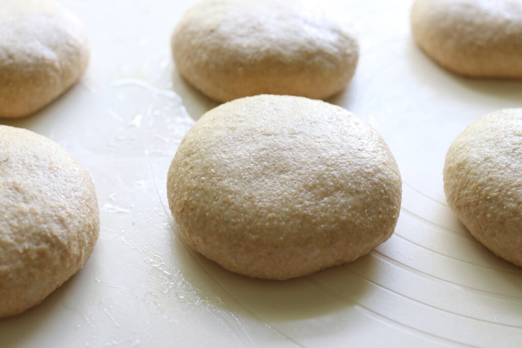 freshly milled brioche buns rising on a baking sheet