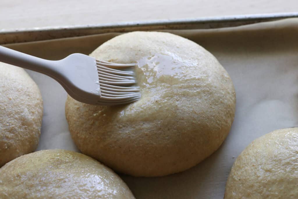 brushing freshly milled brioche burger buns with an egg wash