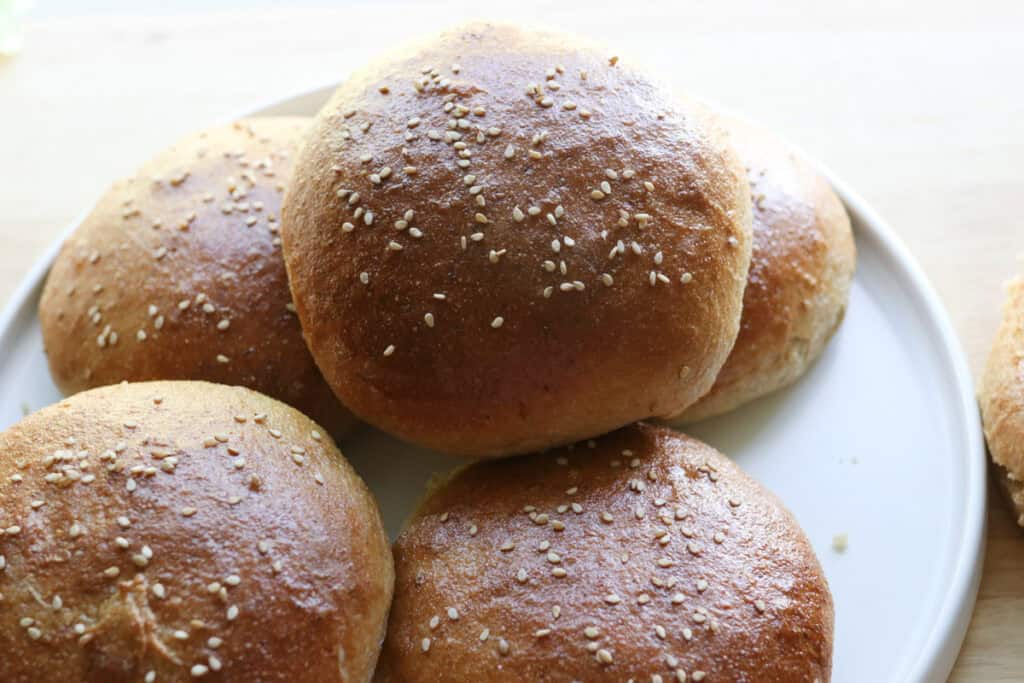 five freshly milled brioche burger buns on a white plate