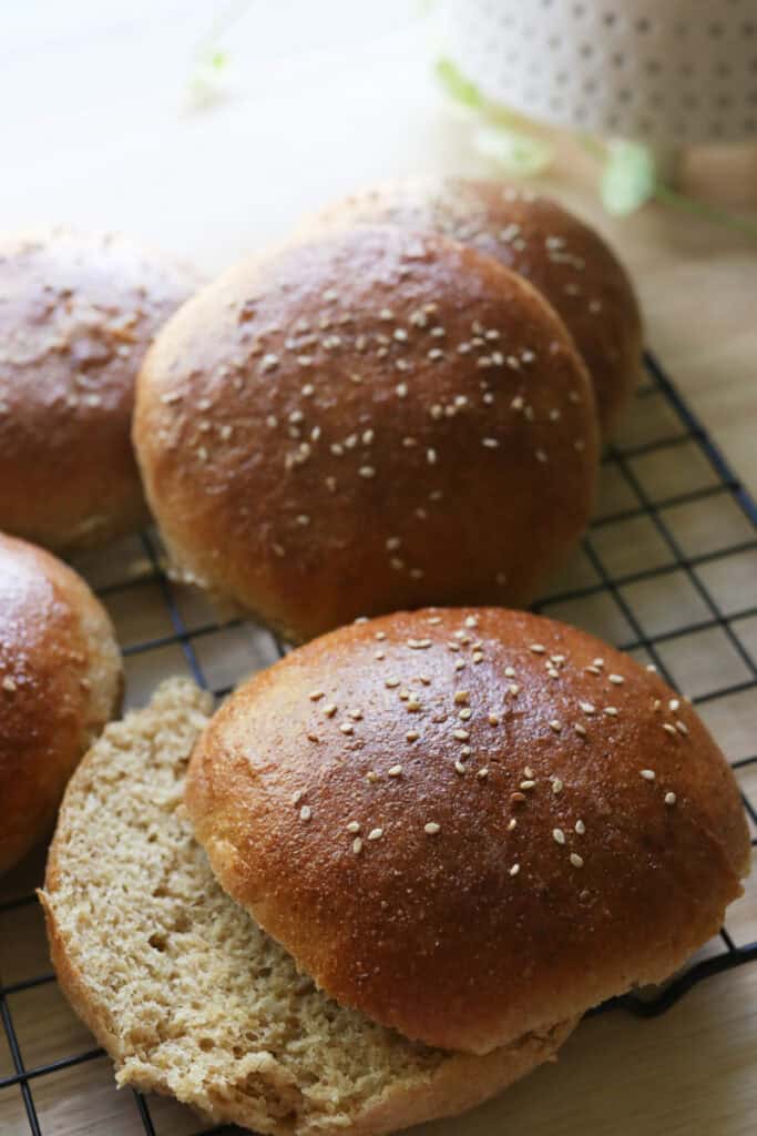 freshly milled brioche burger buns cooling on a rack with one cut in half