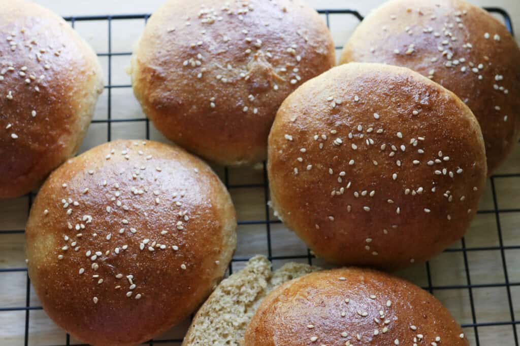 freshly milled brioche burger buns on a black baking rack