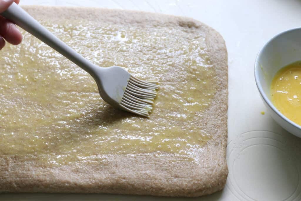 brushing egg wash onto cinnamon swirl dough