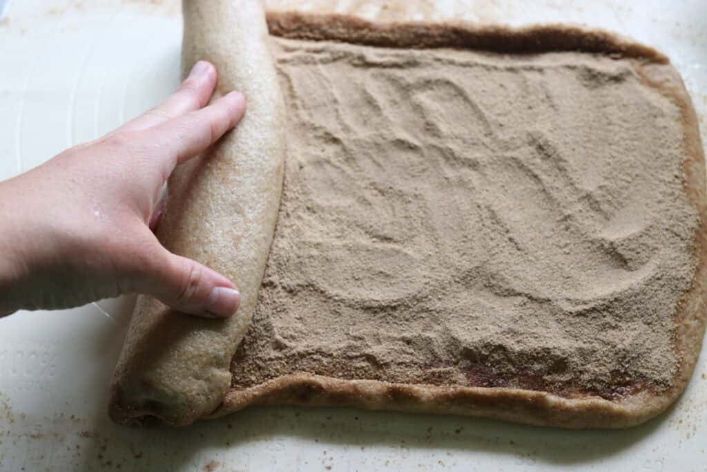rolling up the fresh milled cinnamon swirl bread into a loaf