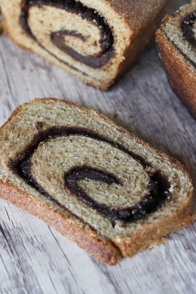 a slice of fresh milled cinnamon swirl bread on a wooden background