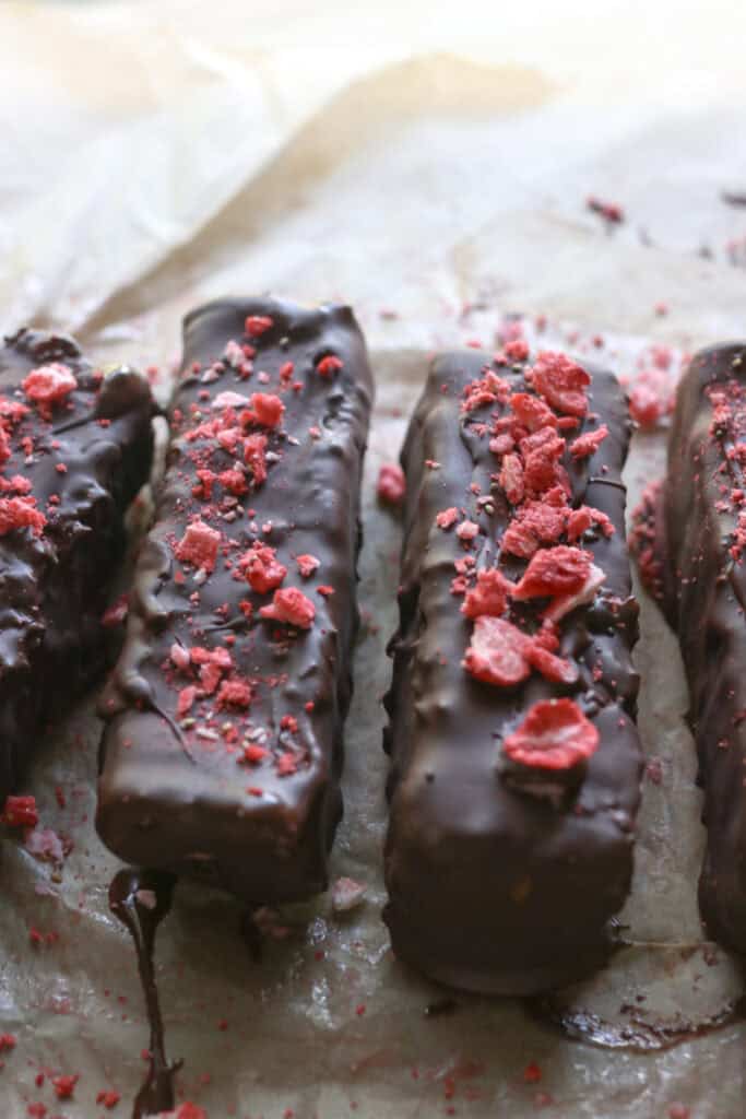 two strawberries & cream coconut bars covered in chocolate and freeze-dried strawberries