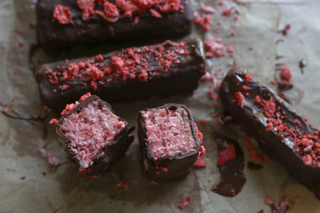 a chocolate covered strawberries & cream coconut bar with coconut filling inside