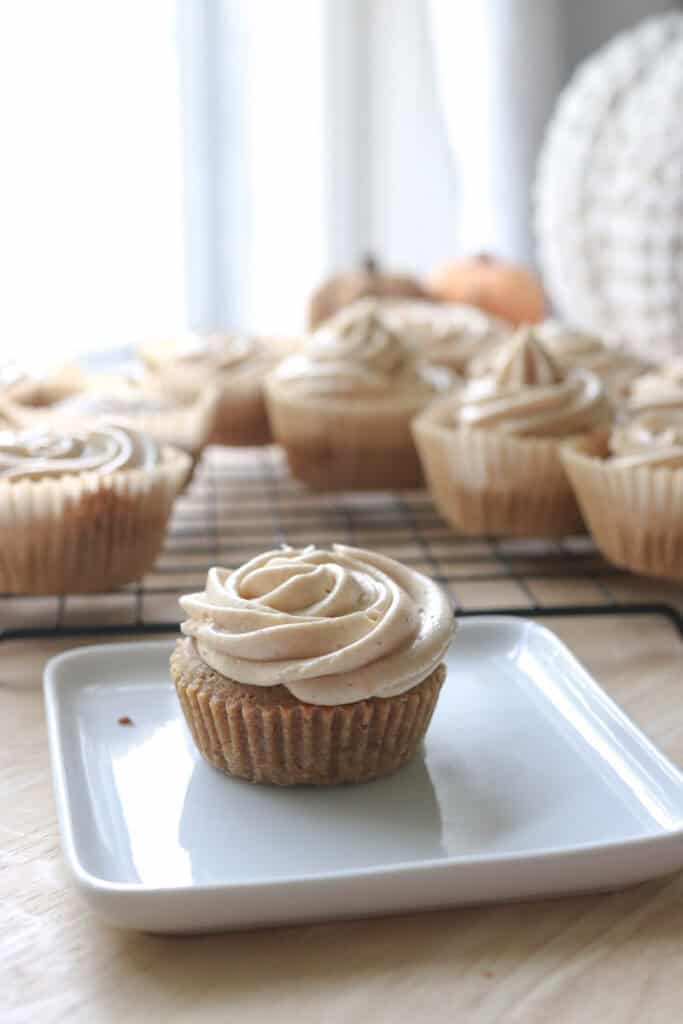 a fresh milled apple cider cupcake with buttercream on a white plate