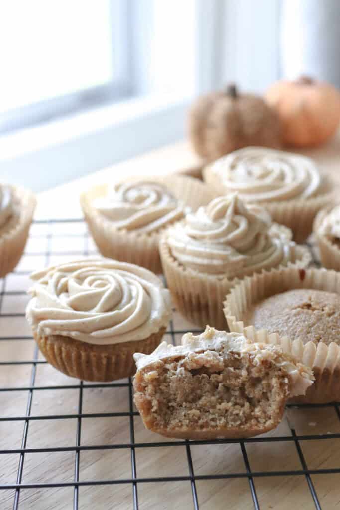 a fresh milled apple cider cupcake cut in half with more apple cider cupcakes behind it