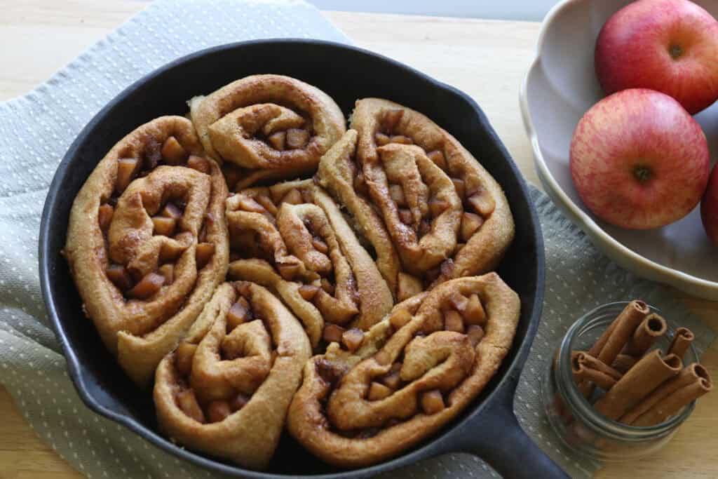  freshly milled apple cinnamon rolls in a skillet that have been baked