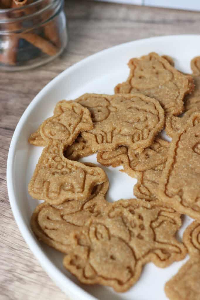 Homemade Animal Crackers with Fresh Milled Flour on a white plate with cinnamon sticks in a glass jar