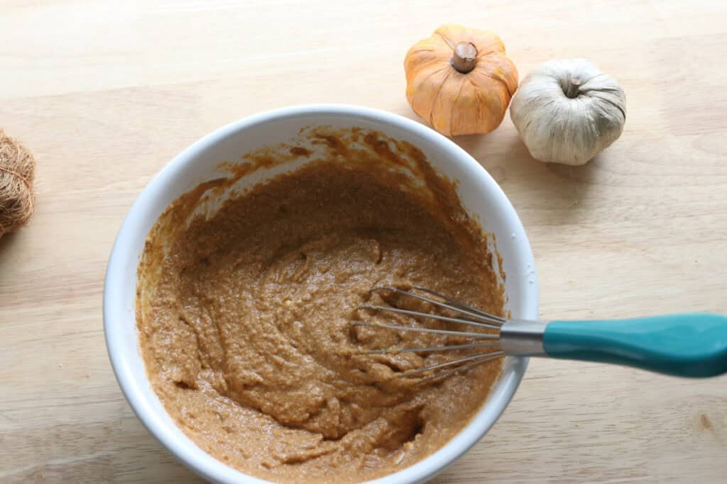 pumpkin donut hole batter in a bowl with a whisk