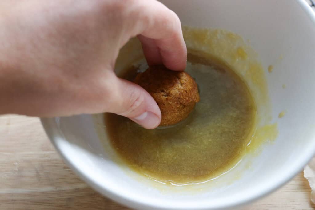 dipping baked pumpkin donut holes in glaze