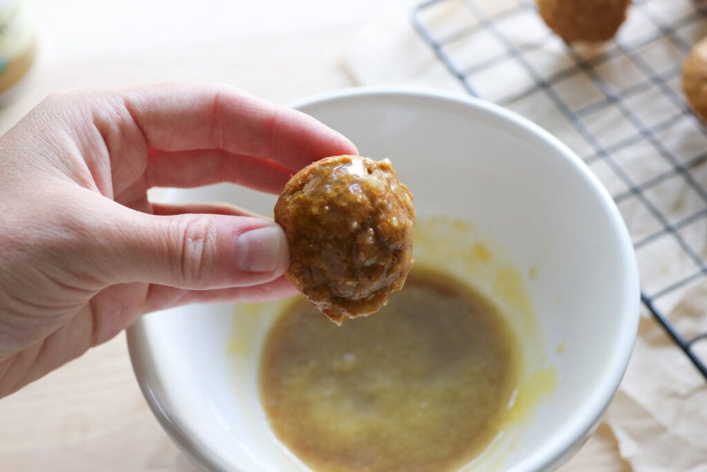 a freshly milled baked pumpkin donut hole that has been dipped in glaze in a white bowl
