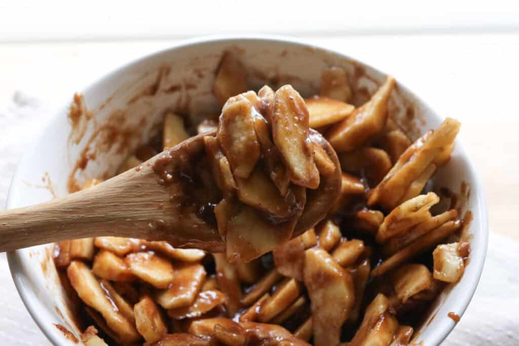 thinly sliced apples covered with maple syrup in a white bowl