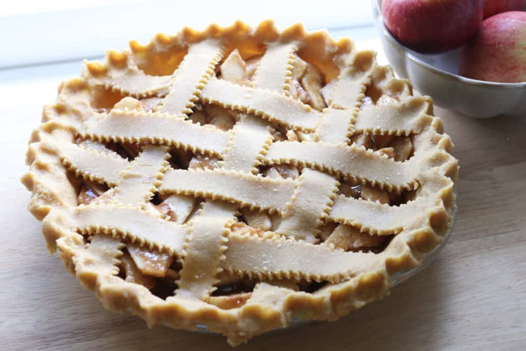 a freshly milled classic apple pie with lattice strips and apples in a bowl