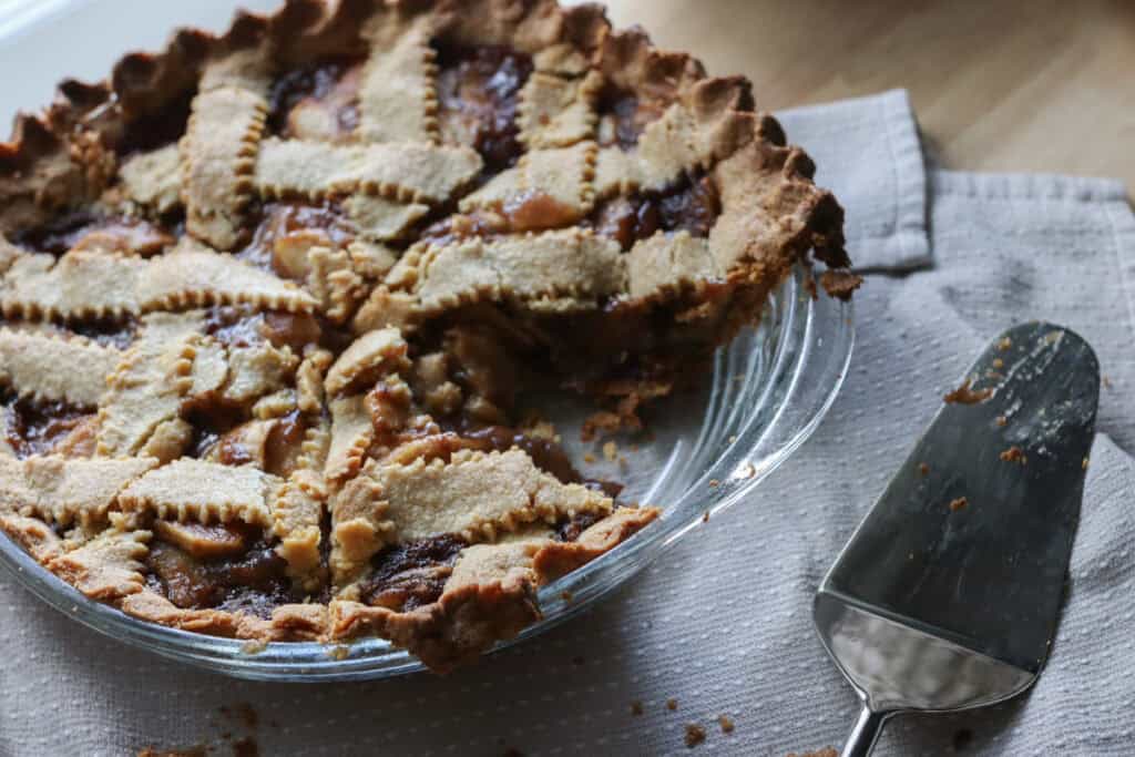 the best freshly milled classic apple pie with a slice taken out and a pie server beside it
