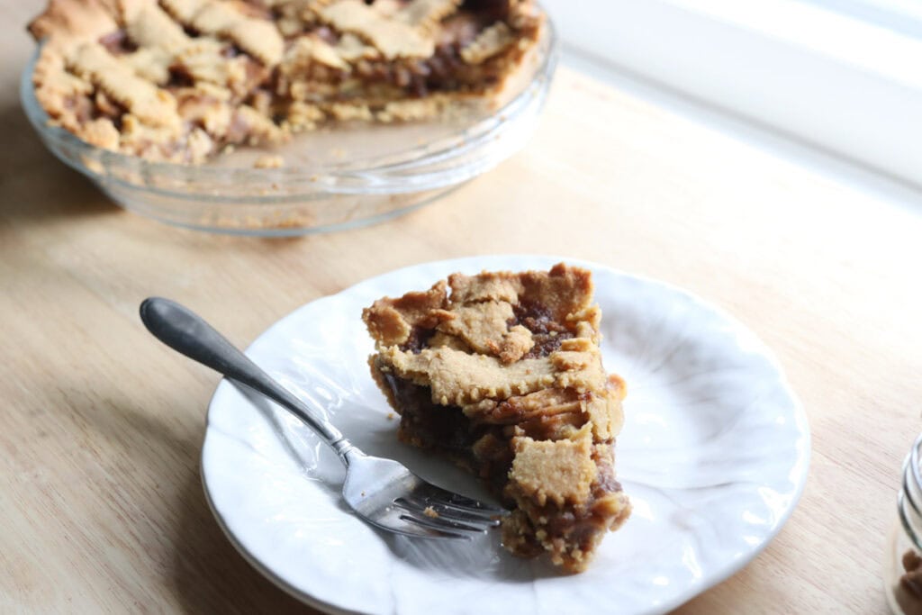 a slice of classic apple pie with freshly milled flour on a white plate with a fork