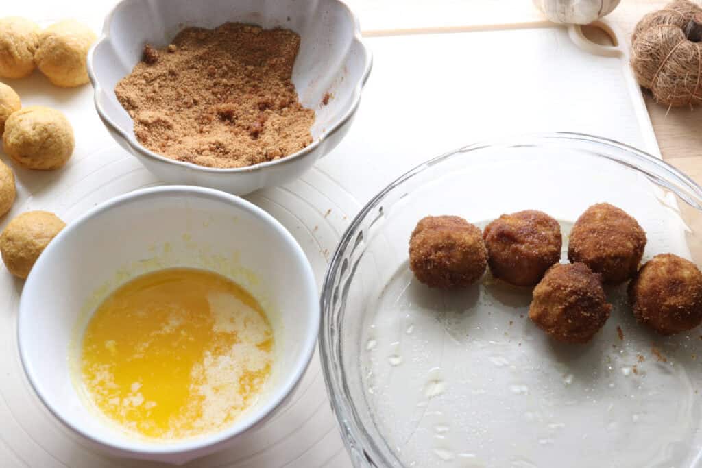 fresh milled pumpkin dough rolled into balls with butter and cinnamon and sugar in bowls
