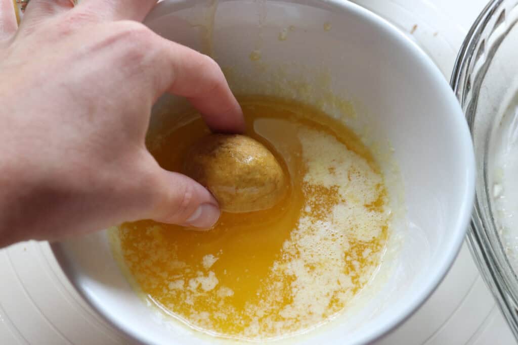 rolling fresh milled pumpkin monkey bread dough in butter