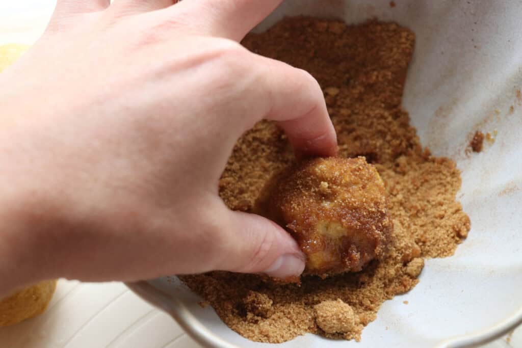 rolling fresh milled pumpkin monkey bread dough in cinnamon and sugar