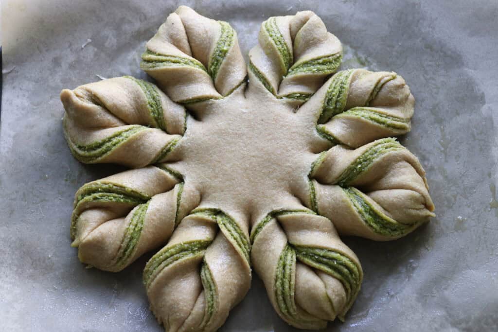 freshly milled parmesan pesto star bread on a piece of parchment paper