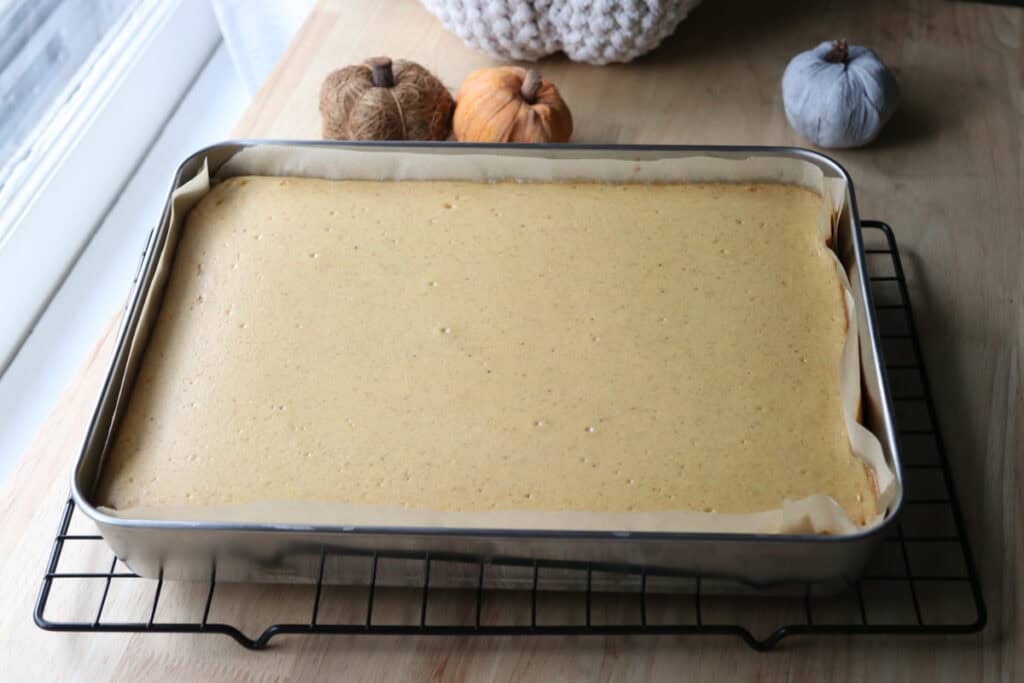 pumpkin cheesecake bars with fresh milled crust that have been baked, cooling on a wire rack