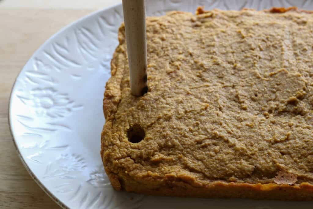 poking holes in Freshly Milled Pumpkin Spice Latte Cake on a white plate