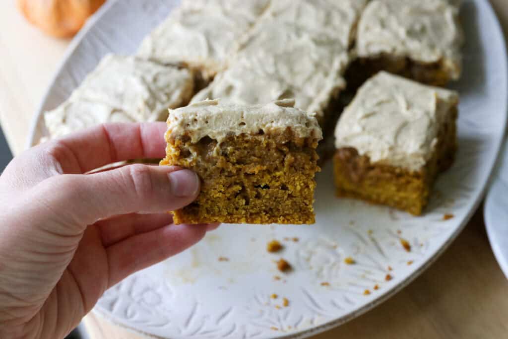 someone holding a slice of Freshly Milled Pumpkin Spice Latte Cake with Frosting