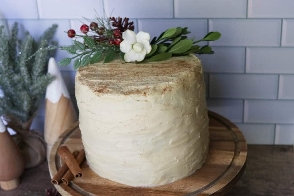 fresh milled gingerbread cake with cream cheese icing on a wooden stand with branches and berries on top